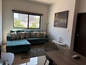 A modern living room with a sectional sofa, a dining table, and a small side table.