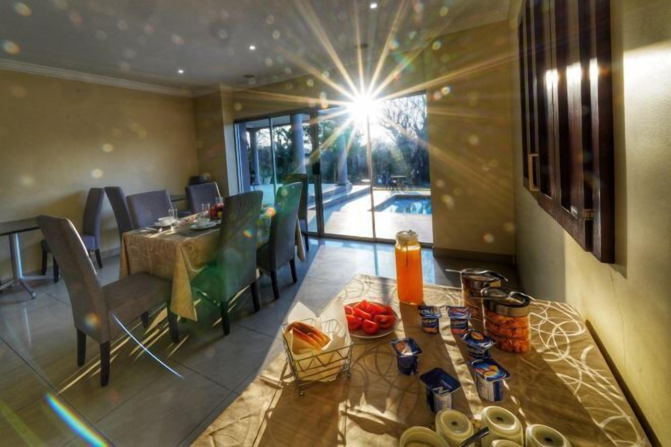 A dining area with a table set for breakfast, a large window with a view of a swimming pool, and a sunburst effect.