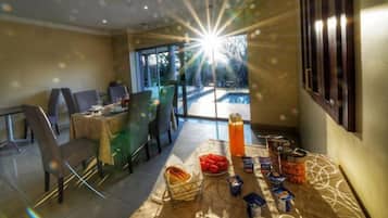 A dining area with a table set for breakfast, a large window with a view of a swimming pool, and a sunburst effect.