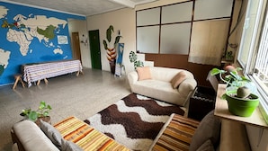 A living room with a world map on the wall, a sofa, a patterned rug, and a green potted plant. - Pachamac House (Guayaquil)