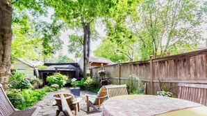 Eine Holzterrasse mit Tisch und Stühlen, umgeben von üppigem Grün und einem Holzzaun.