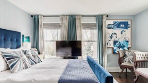 Ein Schlafzimmer mit einem großen Bett, einem Fernseher und einem Sessel.