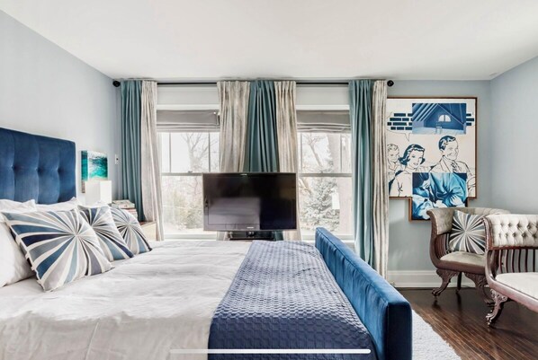 Une chambre avec un grand lit, une télévision et un fauteuil.