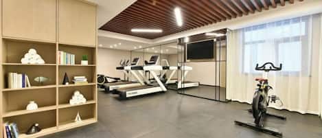 A gym with treadmills, stationary bikes, and a mirrored wall.
