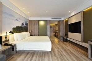 A modern hotel room with a large bed, a flat-screen TV, a desk, and a painting on the wall. - Atour Hotel（Beijing Chaoyang Park Red Scarf Bridge） (Beijing)