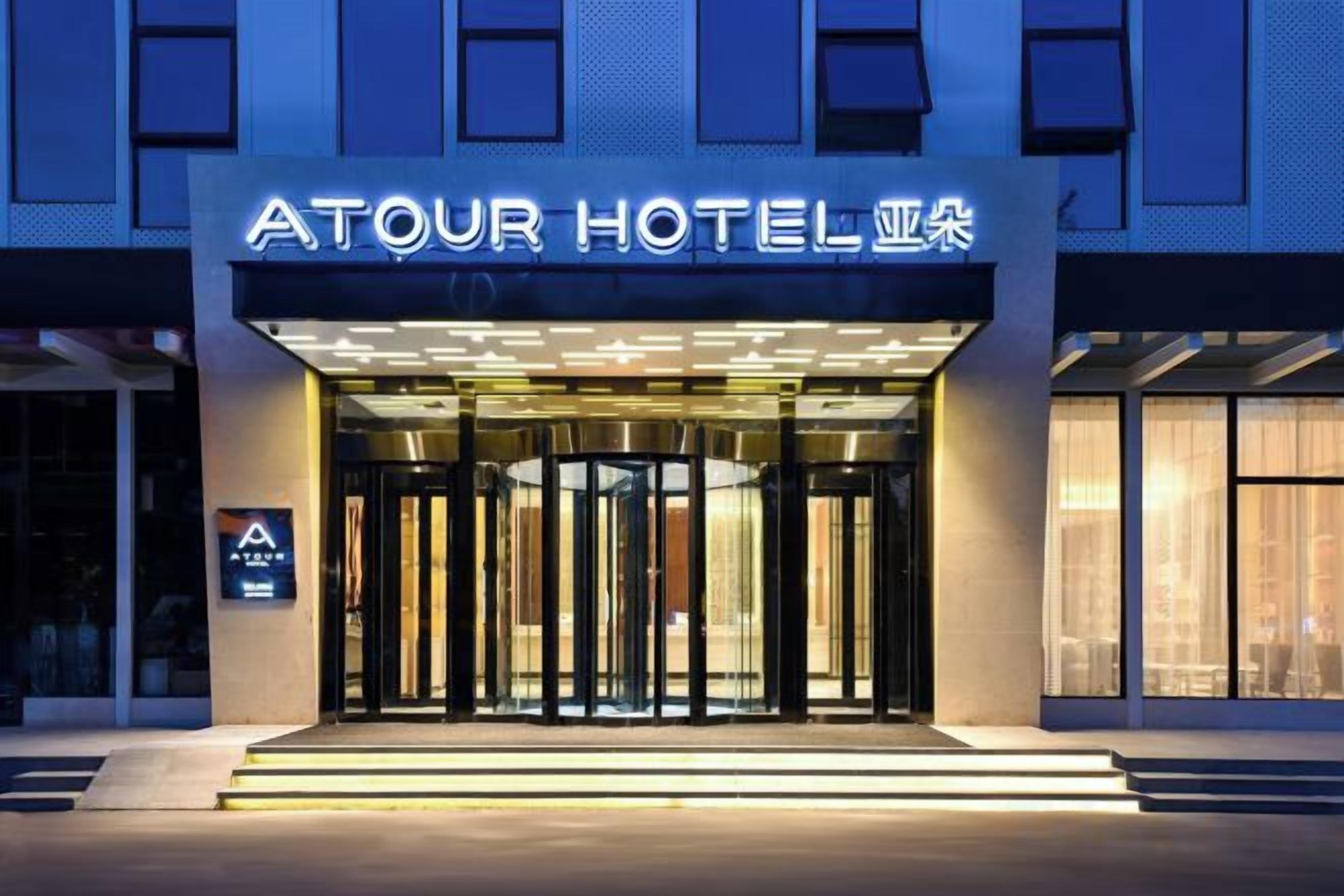 Exterior del hotel Atour, con una entrada destacada, señalización iluminada y un diseño arquitectónico moderno.