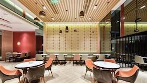 A modern interior with round tables and orange chairs, a patterned wall, and a wooden ceiling. - Atour Hotel（Beijing Chaoyang Park Red Scarf Bridge） (Beijing)