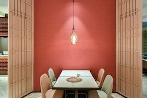 Un'area pranzo con tavolo e sedie, un lampadario a sospensione e una parete rossa.