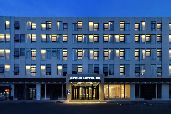 A multi-story hotel with a central entrance, illuminated windows, and a sign indicating it is a hotel.
