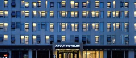 A multi-story hotel with a central entrance, illuminated windows, and a sign indicating it is a hotel.