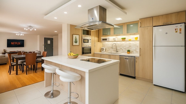 A modern kitchen with a central island, stainless steel appliances, and a dining area with a TV displaying 'NETFLIX'. - Esmeralda Shelter - Jacuzzi (Cuenca)