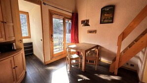 A room with a wooden table and chairs, a sliding glass door leading to an outdoor area, and a staircase. - Bear Hollow D151 (Les Allues)