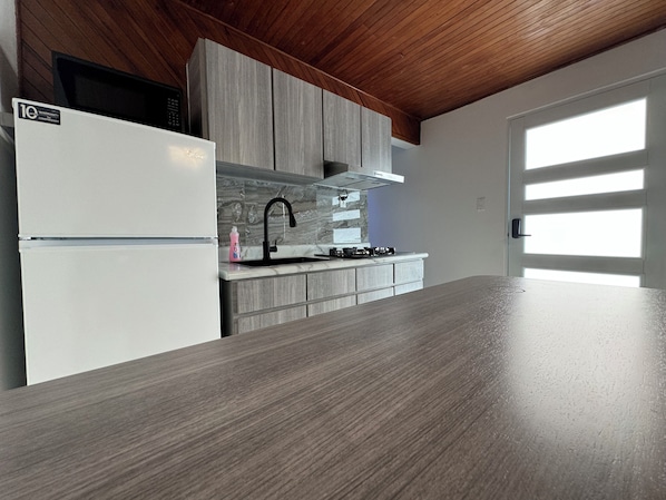 Eine moderne Küche mit einem weißen Kühlschrank, grauen Schränken, einem schwarzen Wasserhahn und einer Marmor-Spritzschutzwand.