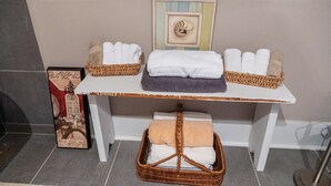 A bathroom with a white vanity, two wicker baskets with towels, a framed picture on the wall, and a small wicker basket on the floor. - Guest House of Kentucky (2 Singles - 2nd Floor) (Lancaster)