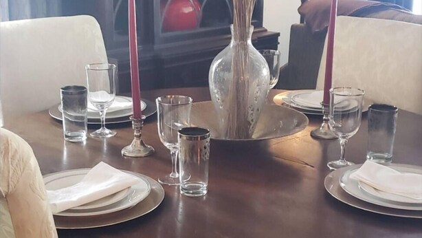 A dining table set for two with a vase of dried plants, candles, and glassware. - The Peaceful Garrard Inn (Lancaster)