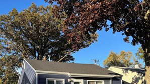 A single-story house with a dark blue exterior, a white front door, and a small front yard with a sidewalk leading to the entrance. - Cozy Home in Madison Heights (Madison Heights)