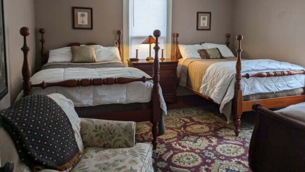 A bedroom with two beds, a chandelier, and a patterned rug. - Gate House (2 Doubles + 1 Single - 2nd Floor) (Lancaster)