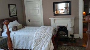 A bedroom with a bed, a fireplace, a door, and a mirror. - Gate House (2 Doubles + 1 Single - 2nd Floor) (Lancaster)