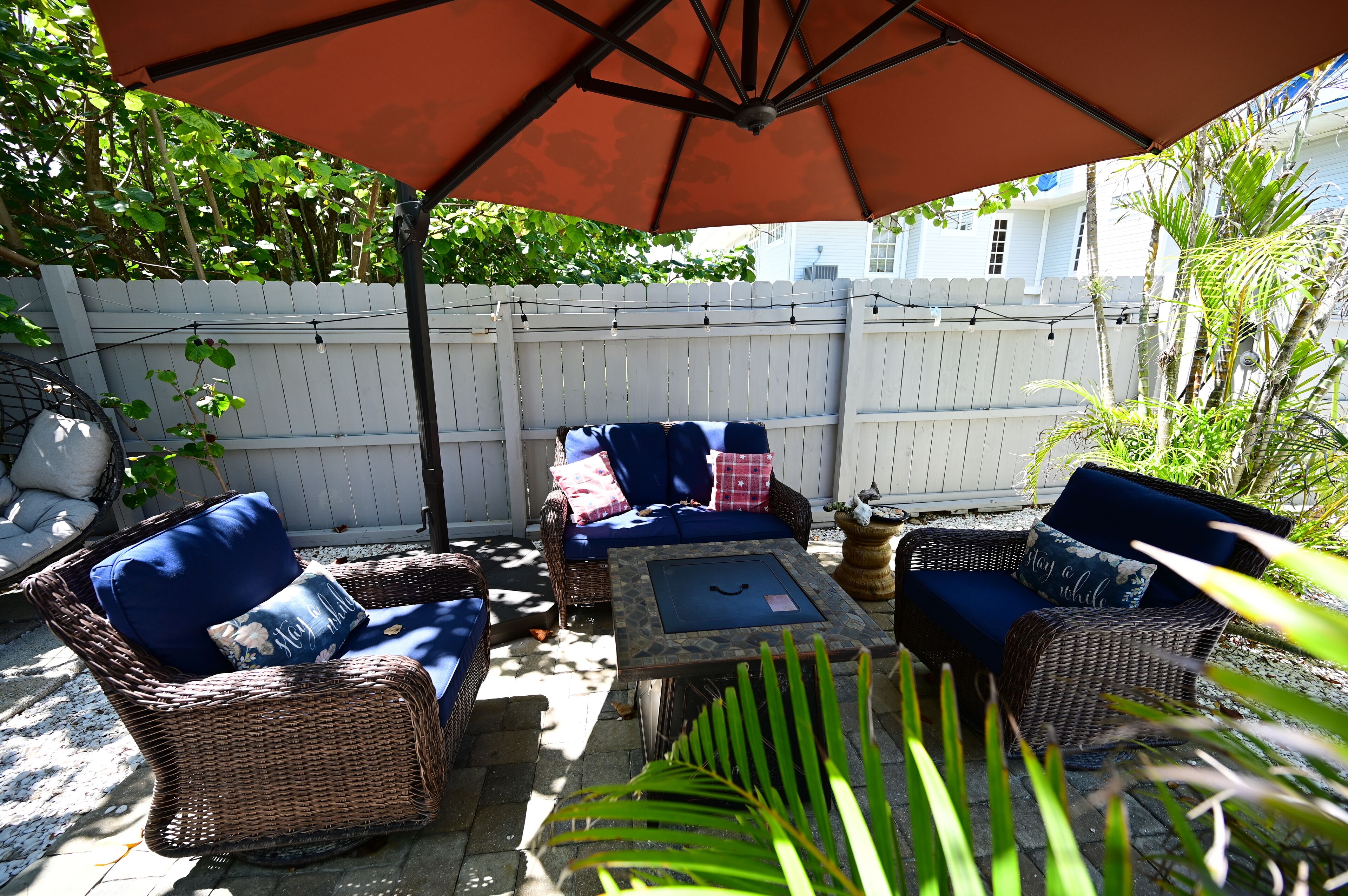 Une terrasse extérieure aménagée avec des meubles en osier, une table en pierre et un grand parasol.