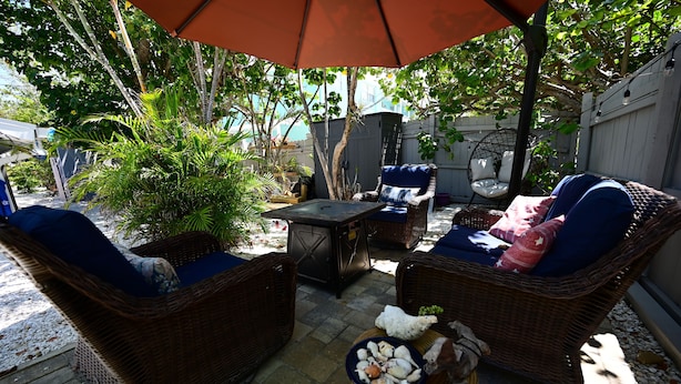 A patio area with wicker furniture, a table, and a bowl of snacks. - Lovely king room in 8 unit Inn in tranquil Sanibel with bikes, beach gear... (Sanibel)