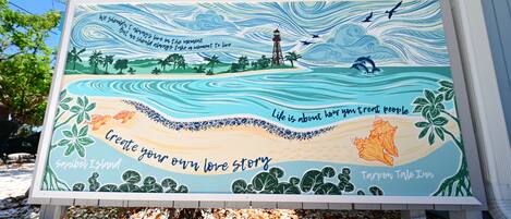 Un letrero colorido con citas inspiradoras y una escena de playa.
