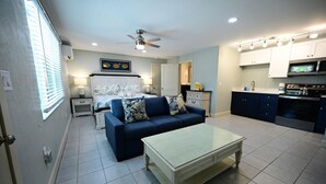 A compact living space with a bed, a sofa, a coffee table, and a kitchenette. - Lovely king room in 8 unit Inn in tranquil Sanibel with bikes, beach gear... (Sanibel)