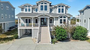 A two-story house with a front porch, a covered entryway, and a small front yard. - Bella Vista II | 3,144 ft to the beach | Private Pool and Hot Tub (Corolla)