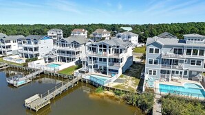 A waterfront residential complex with multiple multi-story houses, a dock, and a swimming pool. - Bella Vista II | 3,144 ft to the beach | Private Pool and Hot Tub (Corolla)