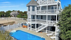Ein zweistöckiges Gebäude mit Pool, Balkon und umzäunter Terrassenbereich.