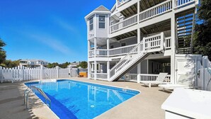 Ein zweistöckiges Gebäude mit Swimmingpool, weißen Geländern und einer überdachten Terrasse.