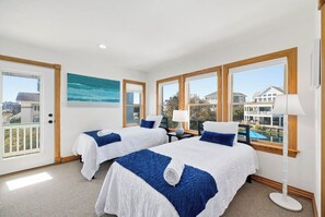 A hotel room with two beds, a balcony, large windows, and a painting of a beach. - Salt and Soul Cottage | 1,228 ft to the beach | Private Pool and Hot Tub (Corolla)