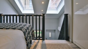 A bedroom with a bed, a skylight, a staircase, and a view of the outside. - Student Only The Chapel (Manchester)