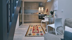 A modern kitchen with a dining area, a staircase, and a living room with a sofa and a coffee table. - Student Only The Chapel (Manchester)