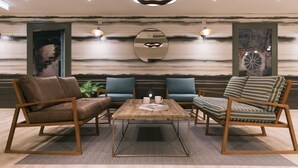A modern living room with a wooden coffee table, two sofas, and two armchairs. - Student Only The Chapel (Manchester)