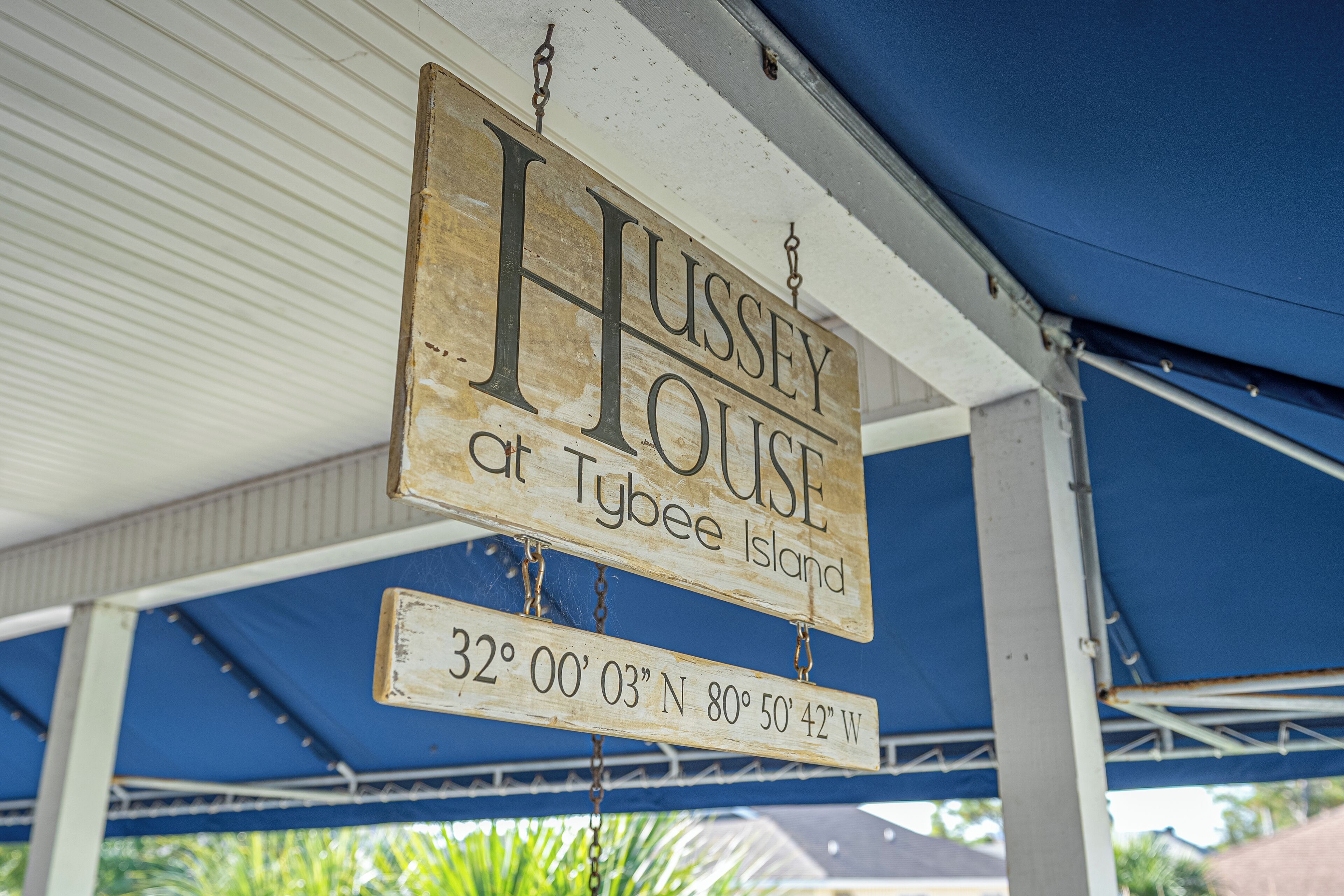 A sign for 'Hussey House at Tybee Island' with coordinates.