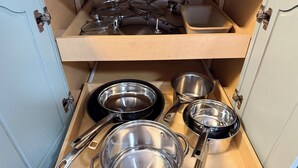 Un tiroir de cuisine contenant des ustensiles de cuisine et des couvercles en acier inoxydable.