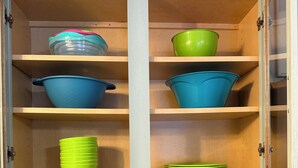 Un meuble de cuisine avec des étagères où sont rangés divers bols de couleurs différentes, et une machine à café posée sur le plan de travail.