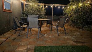 Une terrasse extérieure avec une table et des chaises, des guirlandes lumineuses et une pergola en bois.