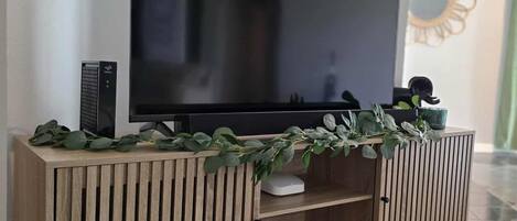 Un mueble de televisión de madera con un televisor de pantalla plana, una planta decorativa y una pequeña estatua.
