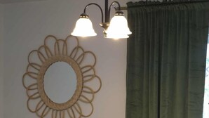 Un coin repas avec une table dressée pour quatre personnes, un miroir décoratif et un vase avec une plante.