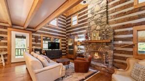 L’intérieur d’une cabane en rondins, avec une cheminée, un plancher en bois et un coin salon confortable.