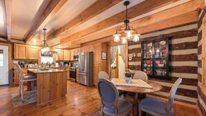 Une cuisine rustique avec des meubles en bois, un îlot central et un coin repas comprenant des chaises et une table.