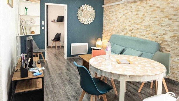 A modern dining area with a round table, chairs, a sofa, and a decorative wall piece.