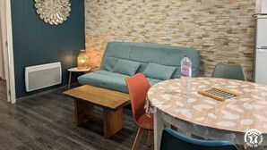 A modern living room with a stone-patterned wall, a blue sofa, a wooden coffee table, and a round table with chairs.