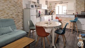 A modern kitchen with a stone wall backsplash, a dining area with a round table, and a sofa.