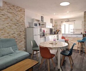 Een moderne keuken met een betegelde muur, een eethoek met een ronde tafel, en een bank.
