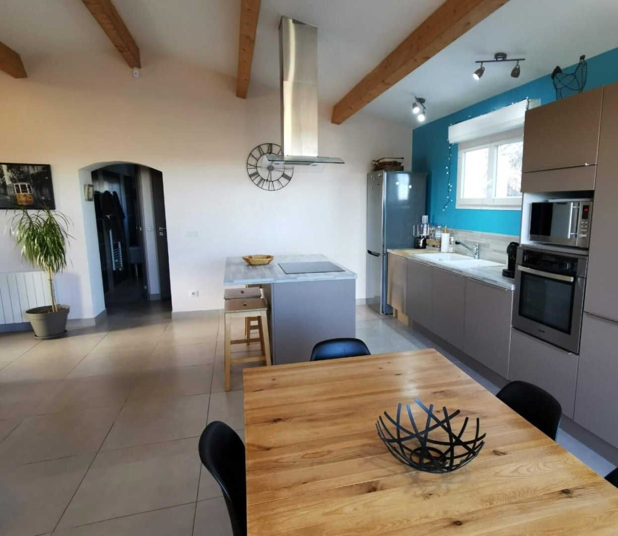 Une cuisine moderne équipée d’appareils électroménagers en acier inoxydable, une table à manger en bois et une plante en pot.