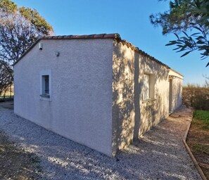 Ein kleines, eingeschossiges Gebäude mit weißer Fassade und rotem Ziegeldach. Es besitzt ein Fenster an der Vorderseite sowie ein weiteres seitlich. Das Gebäude wird von Kies umgeben und eine Auffahrt führt dorthin.