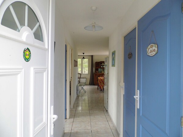 A hallway with a white door on the left and a blue door on the right, leading to a kitchen area. - Merlot - MONTAGNAC (MONTAGNAC)