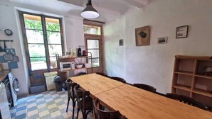 Eine Küche mit Holztisch und Stühlen, einer Mikrowelle und einem Spülbecken. Es gibt Fenster und einen Deckenventilator.